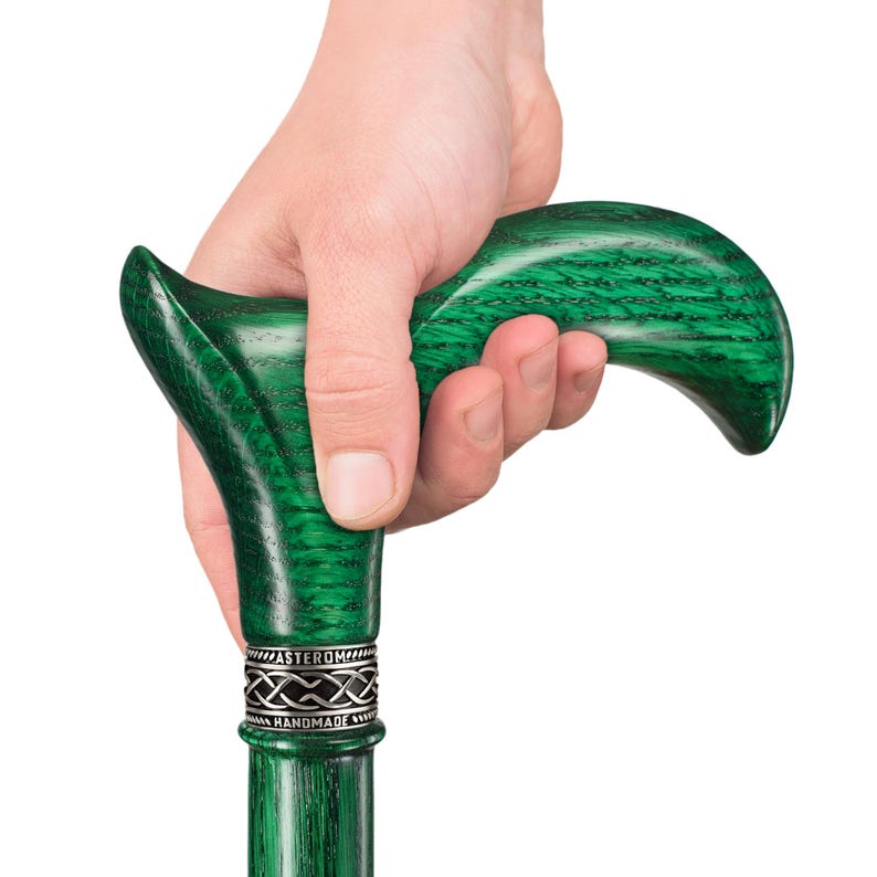 May include: A green wooden walking stick with a carved handle and a silver band with the words "Asterom Handmade".