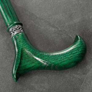 May include: A green wooden walking stick with a silver band and a curved handle.
