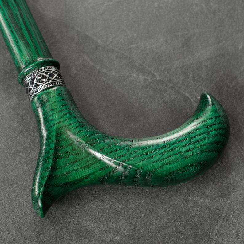 May include: A green wooden walking stick with a silver band and a curved handle.