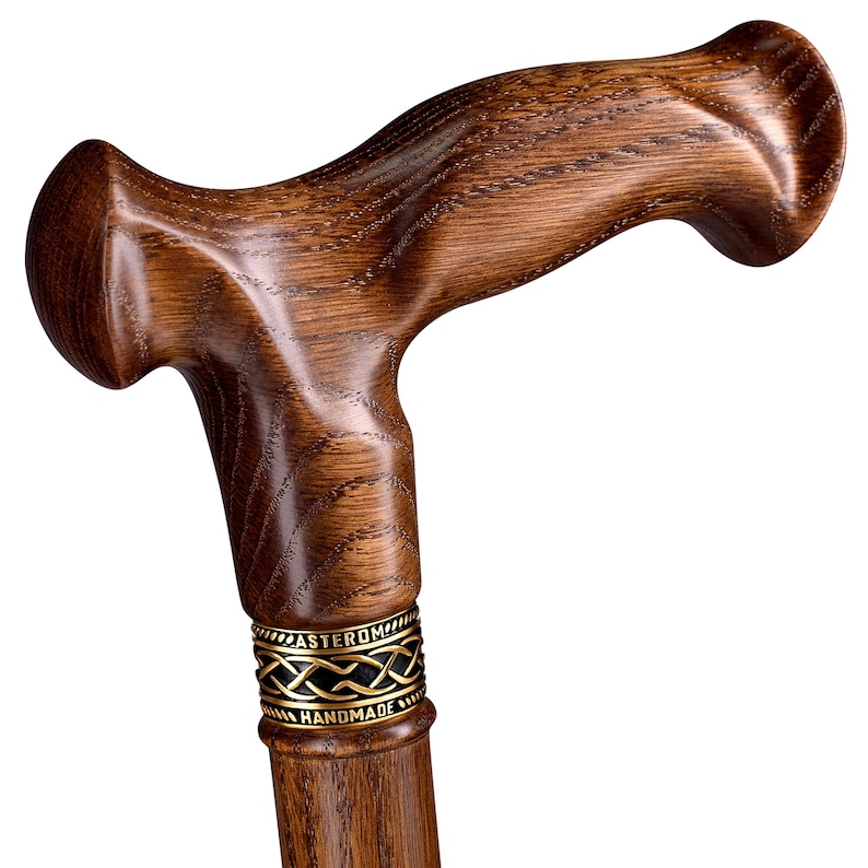 K&ouml;nnte beinhalten: Gehstock aus dunkelbraunem Holz mit gebogenem Griff. Der Stock hat eine polierte Oberfl&auml;che. Ein dekoratives goldfarbenes Band mit aufwendigem Design befindet sich oben. Der Text "ASTEROM HANDMADE" ist auf dem Band zu sehen.