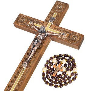 May include: A wooden crucifix with a metal Jesus figure and a rosary. The cross is brown with carved floral designs and gold accents. The rosary has dark brown and cream-colored beads with a small wooden cross.