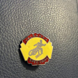 May include: A red and yellow hexagonal pin with the words "VÄLSARNA SPEEDWAY" and a silhouette of a speedway rider.