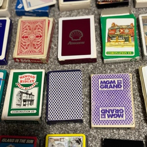 May include: A collection of playing cards with various designs. Some cards feature images of buildings, while others have a simple geometric pattern. The cards are all in a standard playing card size.