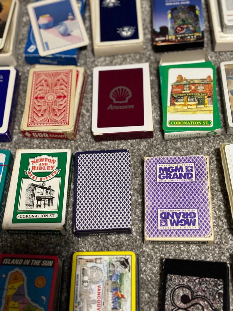 May include: A collection of playing cards with various designs. Some cards feature images of buildings, while others have a simple geometric pattern. The cards are all in a standard playing card size.