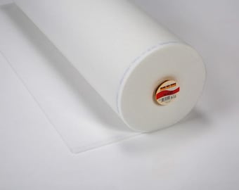 May include: A large roll of white fabric, possibly batting or interfacing, is displayed on a white surface. The roll is cylindrical, with a visible label on one end. A portion of the fabric is unrolled, lying flat.