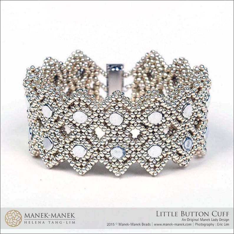 May include: A silver beaded cuff bracelet with a geometric design. The bracelet features small, round silver beads and larger, flat, circular accents. The text "LITTLE BUTTON CUFF" is visible. The bracelet is approximately 5 cm wide.