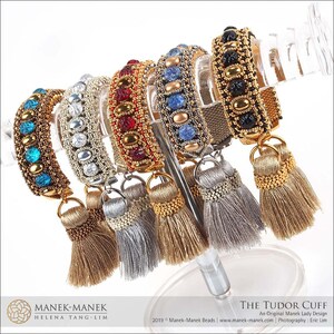 Peut inclure: Un ensemble de sept bracelets en perles avec des perles color&eacute;es et des accents dor&eacute;s. Chaque bracelet est dot&eacute; d'un pompon &agrave; l'extr&eacute;mit&eacute;. Les bracelets sont pr&eacute;sent&eacute;s sur un support transparent.