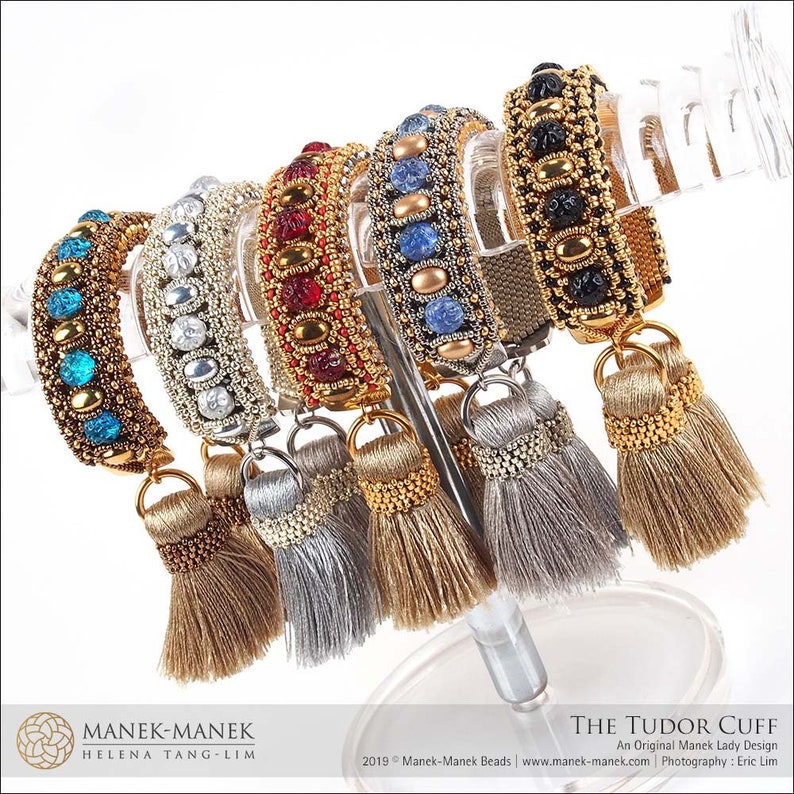 Peut inclure: Un ensemble de sept bracelets en perles avec des perles color&eacute;es et des accents dor&eacute;s. Chaque bracelet est dot&eacute; d'un pompon &agrave; l'extr&eacute;mit&eacute;. Les bracelets sont pr&eacute;sent&eacute;s sur un support transparent.