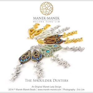 Op de afbeelding: Een paar gouden, zilveren en blauwe parel oorbellen met een bloemmotief. De oorbellen worden "The Shoulder Dusters" genoemd en zijn een origineel ontwerp van Manek Lady.