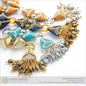Op de afbeelding: Een close-up van een kralenketting met driehoekige hangers in tinten goud, turquoise en blauw. De ketting heeft een kwast met gouden en zilveren kralen.