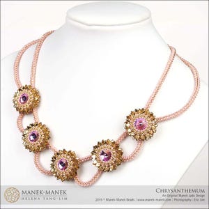 May include: A pink and gold beaded necklace with five flower-shaped pendants. Each pendant features a pink crystal surrounded by gold beads. The necklace is on a white mannequin.