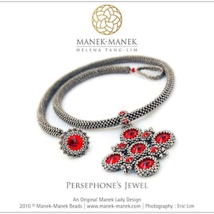 May include: A silver necklace with a red gemstone pendant. The pendant is a geometric design with multiple red gemstones. The necklace is called "Persephone's Jewel" and is an original Manek Lady design.