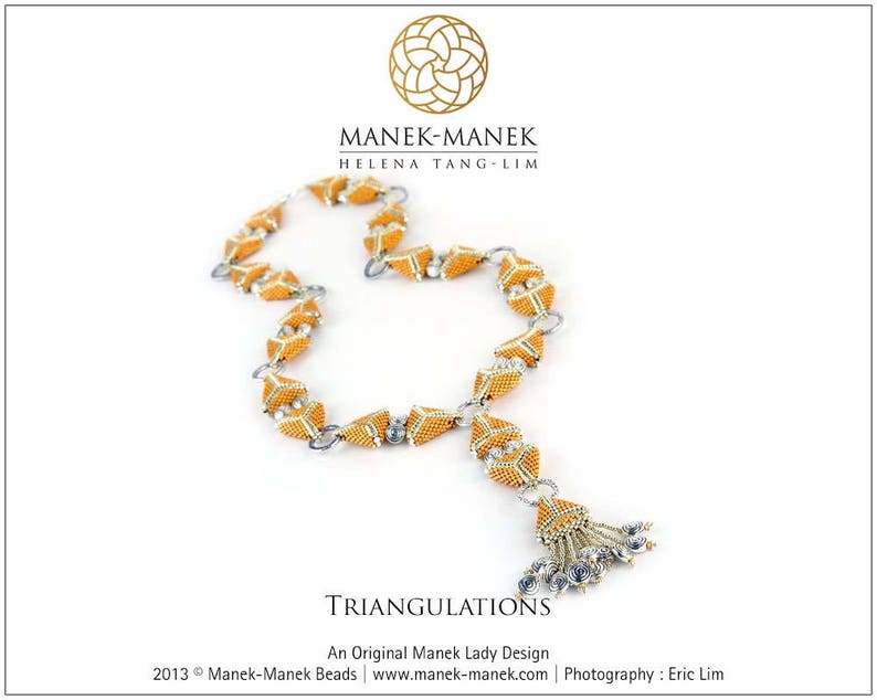 Op de afbeelding: Een gouden en zilveren ketting met een geometrisch ontwerp. De ketting is gemaakt van kleine kralen en heeft een kwast aan het einde. De ketting heet "Triangulations" en is een origineel ontwerp van Manek Lady.