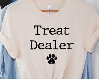May include: A cream-coloured t-shirt with the text "Treat Dealer" and a black paw print.