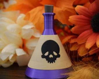 May include: A small purple glass bottle with a cork stopper and a white label featuring a black skull design. The bottle is sitting on a wooden surface.