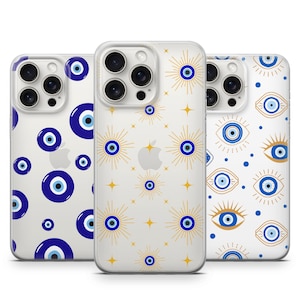 May include: Three clear phone cases with a white background and blue and gold evil eye designs. The cases are for an iPhone.