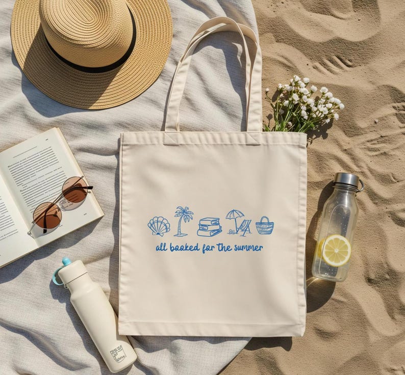 Blue outline illustration featuring a seashell, palm tree, stack of books, beach chair with umbrella, and a beach bag. Below the artwork, the phrase 'all booked for the summer' is written in playful, handwritten-style font.