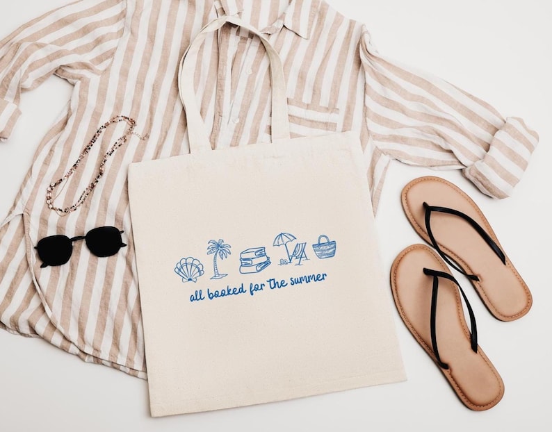 Blue outline illustration featuring a seashell, palm tree, stack of books, beach chair with umbrella, and a beach bag. Below the artwork, the phrase 'all booked for the summer' is written in playful, handwritten-style font.