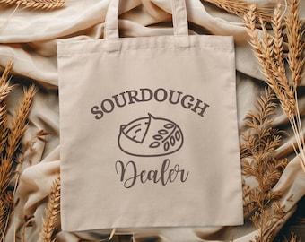 May include: A white canvas tote bag with a brown graphic of a sourdough loaf and the text "Sourdough Dealer".