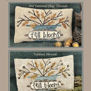 May include: A beige punch needle cushion with a floral design and the text "Fall Blooms." The cushion features a vase with brown and gold leaves. Finished piece measures 14 cm x 21.6 cm.