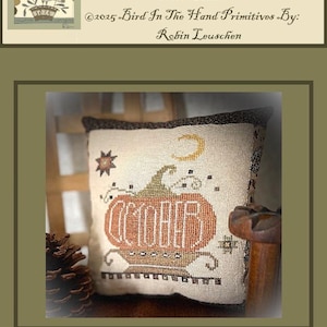 May include: A cross-stitch pillow with a pumpkin design. The word "OCTOBER" is stitched in orange within the pumpkin. The pillow also features a crescent moon and star accents. The text "October Pumpkin Cross Stitch" is at the top.