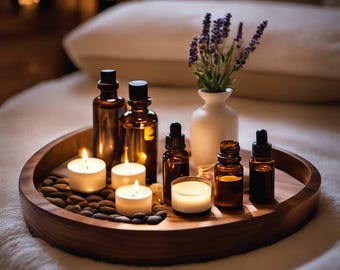 Op de afbeelding: Een houten dienblad met amberkleurige glazen flessen, brandende kaarsen en een kleine witte vaas met lavendel. Het dienblad is gevuld met kleine stenen. De scène roept een spa- of wellness-thema op.