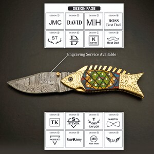 May include: A decorative folding knife with a fish-shaped handle. The handle is gold-colored with colorful inlaid details. The blade is silver with a patterned design. The image also shows engraving design options, including text and symbols. The text "Best Dad" is visible.