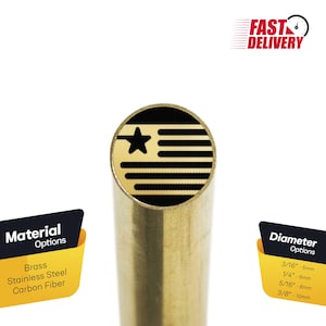 Puede incluir: Primer plano de un bolígrafo de metal dorado con un diseño negro y dorado que presenta una estrella y rayas. El bolígrafo está disponible en latón, acero inoxidable y fibra de carbono. Las opciones de diámetro son 3/16 pulgadas (5 mm), 1/4 pulgadas (6 mm), 5/16 pulgadas (8 mm) y 3/8 pulgadas (10 mm).