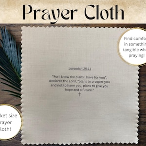 May include: A beige prayer cloth with a scalloped edge. The cloth features the text "Prayer Cloth" in black lettering at the top and a Bible verse from Jeremiah 29:11 in black lettering at the bottom. The text reads: "For I know the plans I have for you", declares the Lord, "plans to prosper you and not to harm you, plans to give you hope and a future."