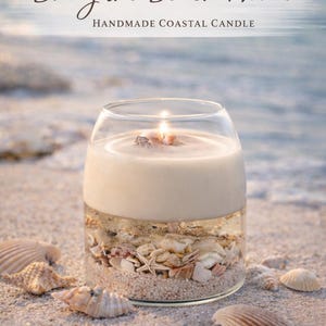 May include: A handmade coastal candle in a clear glass jar, layered with sand and seashells. The candle is lit, with the text "Bring the Beach Home" above. The candle sits on a sandy beach with seashells scattered around.