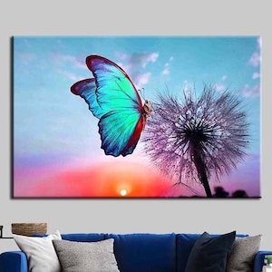 May include: A vibrant blue butterfly with black markings lands on a purple dandelion with a sunset background.