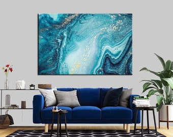 May include: Abstract painting with blue and gold swirls. The painting is framed and hanging on a wall above a blue sofa.