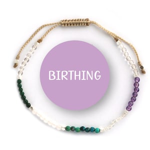 May include: A beaded bracelet with a light brown cord, featuring clear, green, and purple beads. The bracelet has a tag with the word "BIRTHING" on it.