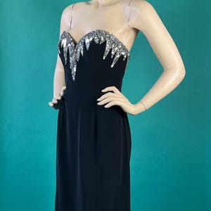 May include: A black strapless dress with a silver sequined bodice. The sequins are arranged in a cascading pattern.