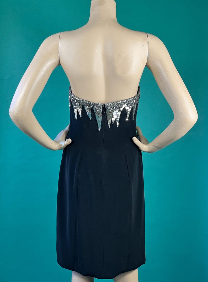 May include: A black strapless dress with a silver sequined bodice. The sequins are arranged in a cascading pattern.