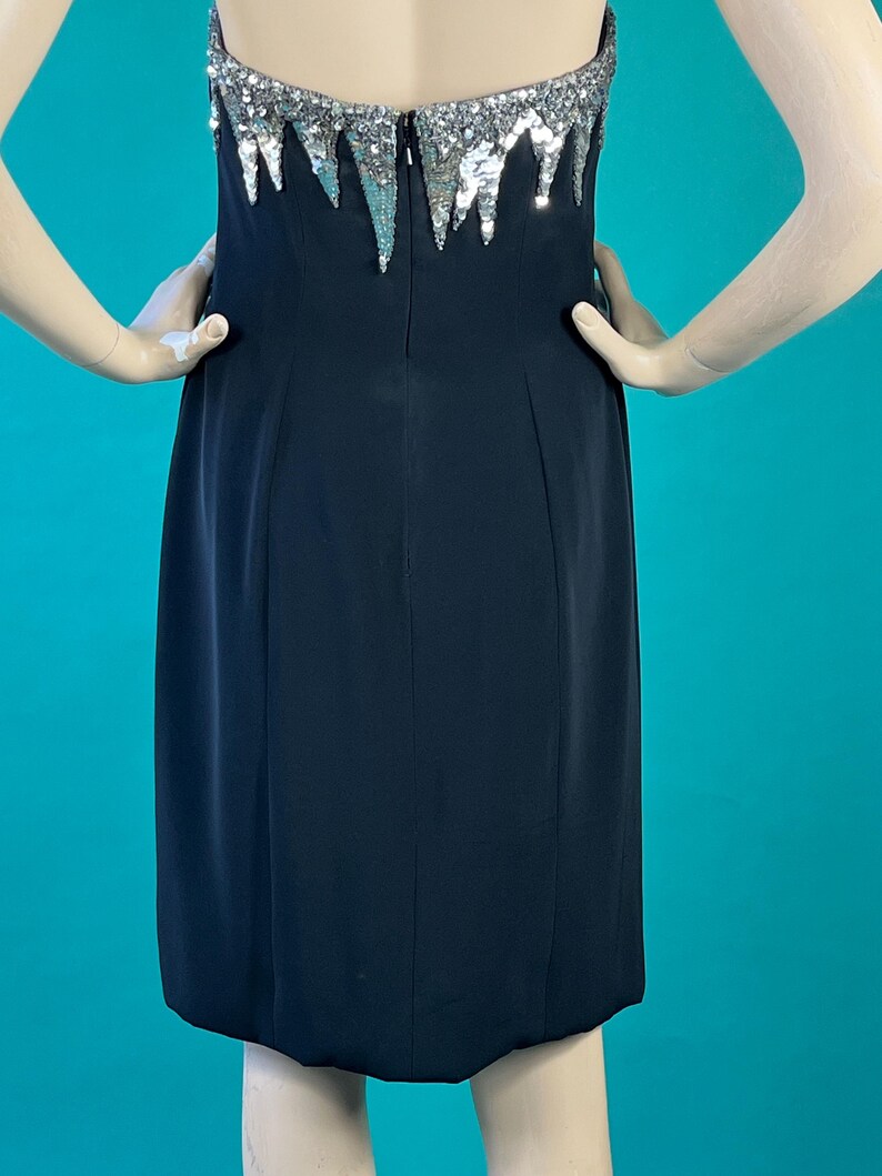 May include: A black strapless dress with a silver sequined bodice. The sequins are arranged in a cascading pattern.