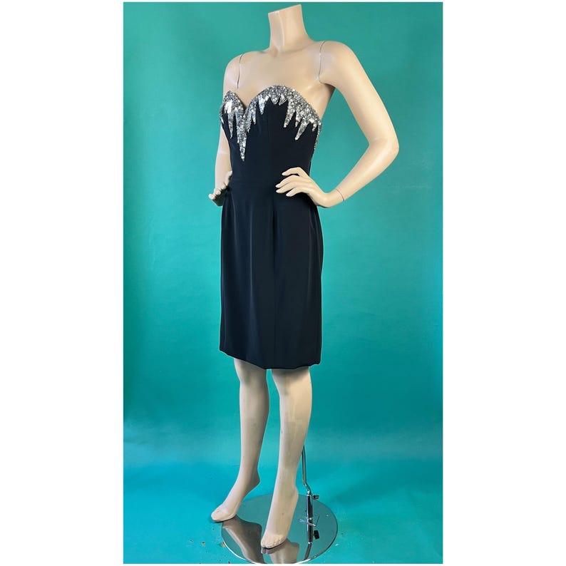 May include: A black strapless dress with a silver sequined bodice. The dress is fitted and has a short skirt.