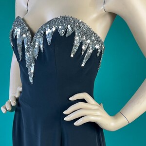 May include: A black strapless evening gown with a silver sequined bodice. The sequins are arranged in a cascading pattern.