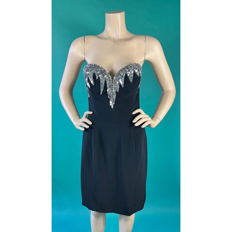 May include: A black strapless dress with a silver sequined bodice. The sequins are arranged in a cascading pattern.