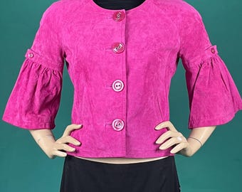 May include: A bright pink suede jacket with three-quarter length sleeves and large buttons down the front. The jacket has a round neckline and flared sleeves. The jacket is displayed on a mannequin.