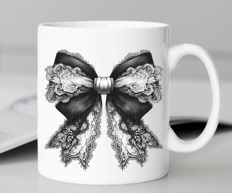 May include: White ceramic mug featuring a black and white lace bow design. The bow is tied with a silver ribbon.