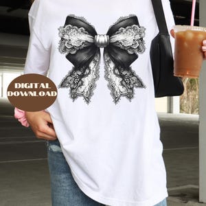 May include: A white t-shirt featuring a black and white lace bow design.