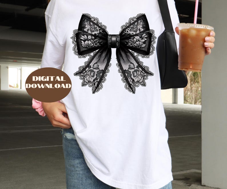 May include: A white t-shirt with a black lace bow design. The bow has a floral pattern and is centered on the shirt.