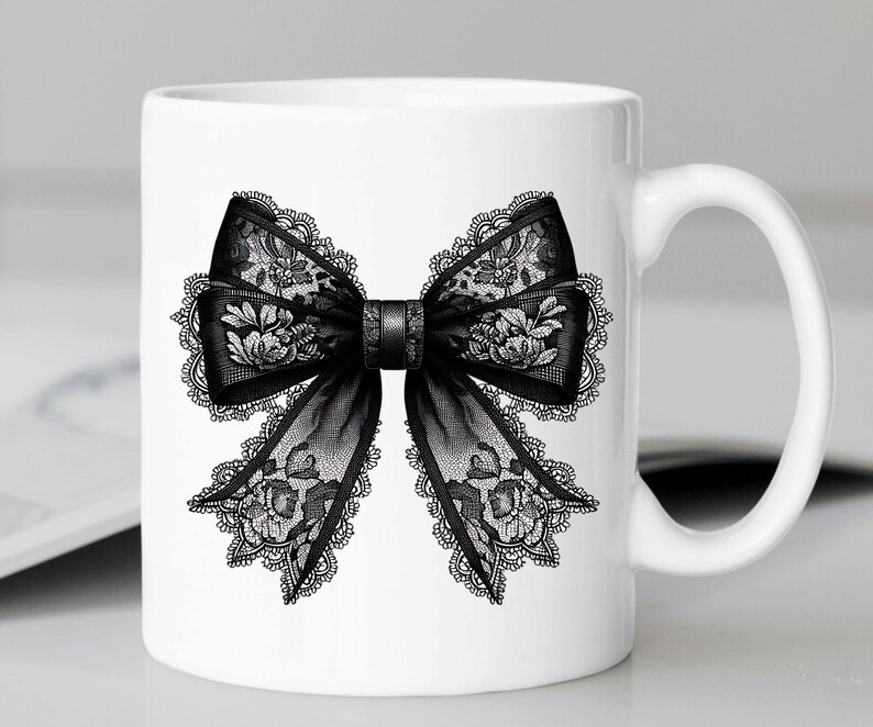 May include: White ceramic mug with a black lace bow design. The bow is detailed with intricate floral patterns.