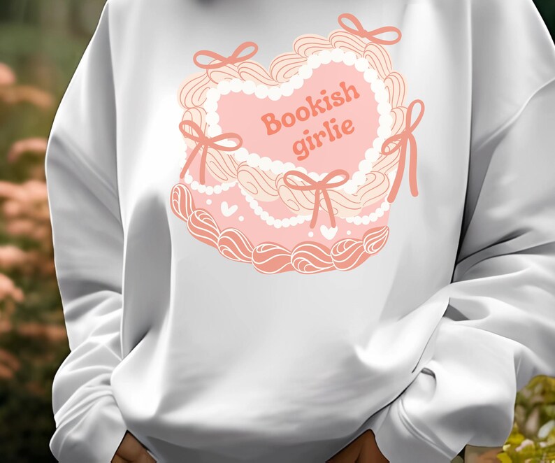 May include: White sweatshirt with a pink heart-shaped design and the text "Bookish girlie" in pink.
