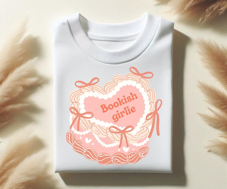 May include: White t-shirt with a pink and white heart-shaped design and the text "Bookish girlie" in orange.