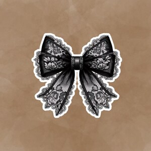 May include: A black lace bow with a white background. The bow is tied in a knot and has a decorative design.