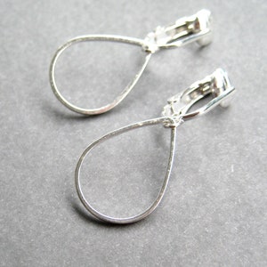 May include: A pair of silver teardrop shaped clip-on earrings.