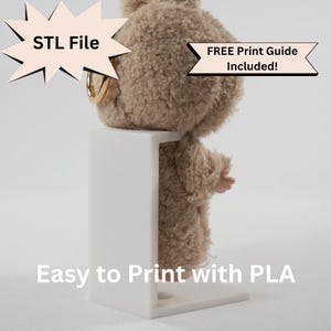 Może przedstawiać: Pluszowa, jasnobrązowa figurka misia prezentowana jest na białym stojaku. Widoczny jest tekst "STL File" i "FREE Print Guide Included!". Widoczny jest również tekst "Easy to Print with PLA".