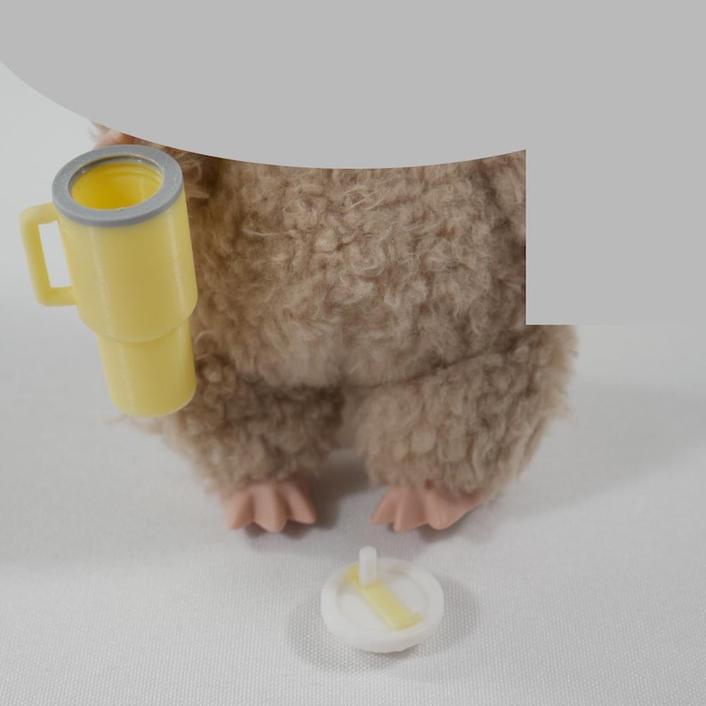 May include: A plush, brown toy animal with pink feet and a yellow cup with a gray rim. A small, white and yellow toy is on the surface. The toy animal is holding the cup.